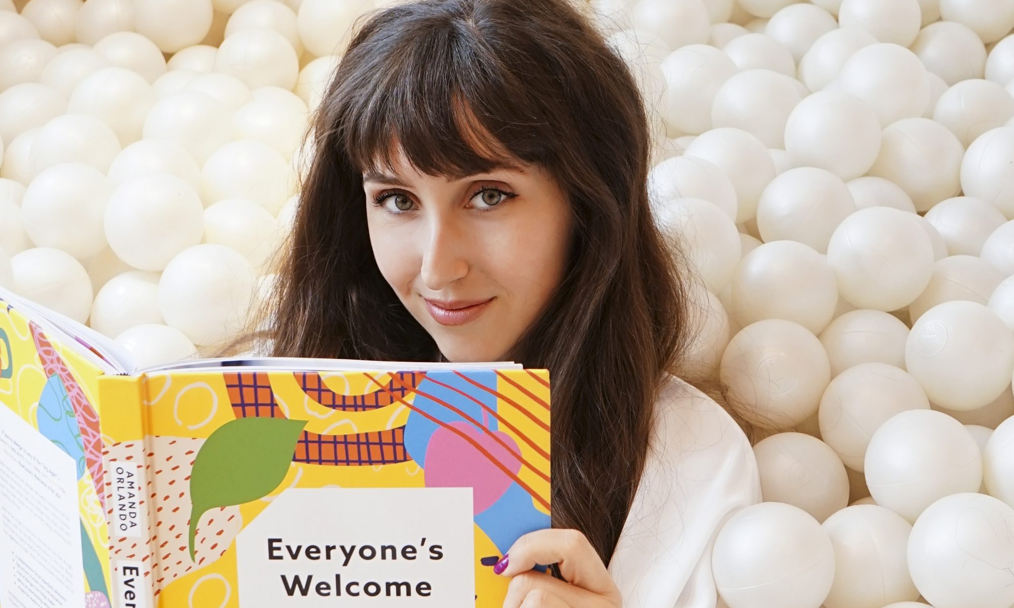 beautiful-young-lady-with-brown-hair-sits-in-ball-pit-reading-cookbook