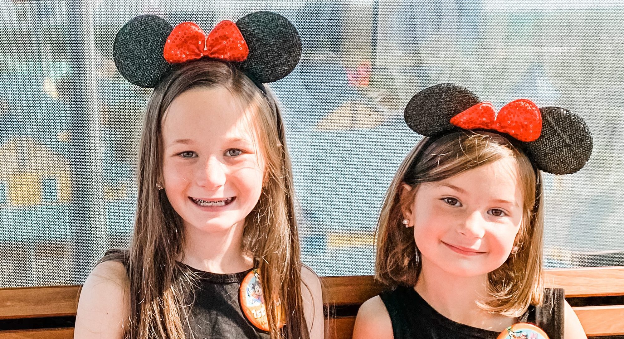 two-girls-sit-on-bench-at-Disney-World-with-Mickey-Mouse-hats