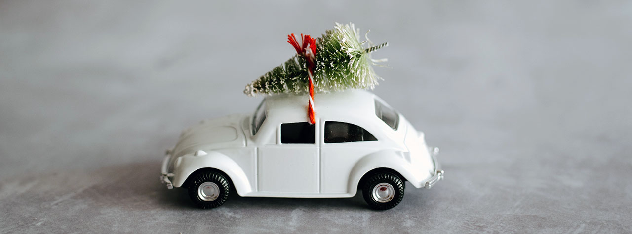 White Volkswagen has Christmas Tree tied on top. Image by Annie Spratt on Unsplash.