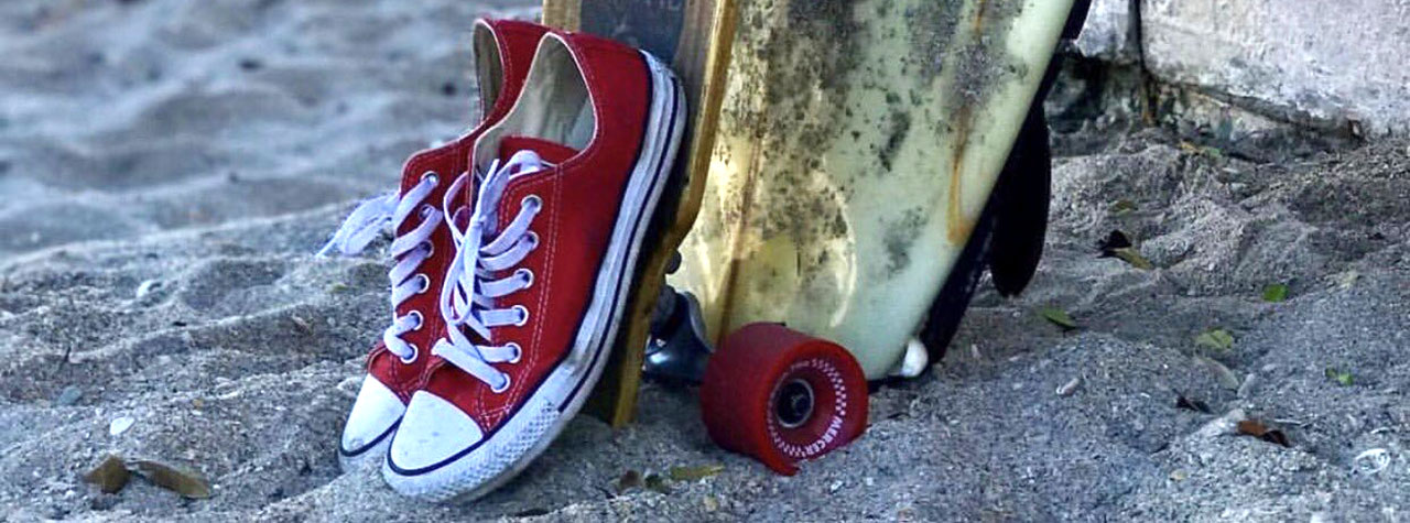 sand-skatboard-surf-board-and-red-sneakers-symbolizing-the-memory-of-oakley-debbs-a-young-boy-taken-too-soon-by-fatal-anaphylaxis