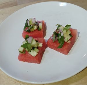 3 squares of watermelon topped with a red onion and cucumber mixture for flavor. Watermelon Bite recipe from Allergy Dragon.