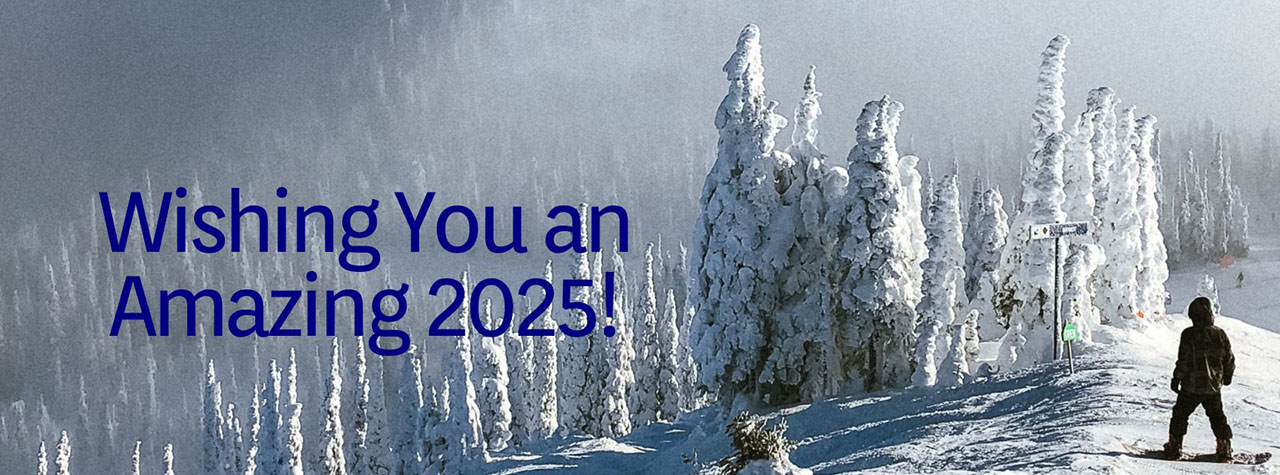 Snowboarder at bottom right of image contemplates a vast snow covered mountain vista before tackling the slope. Image by Holly Mandarich on Unsplash. Text in blue says 'Wishing You an Amazing 2025'