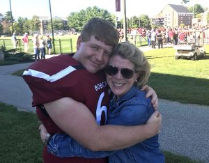 Mom hugs football playing son after a game.